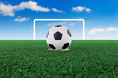 Digital composite of soccer ball on playing field against sky 