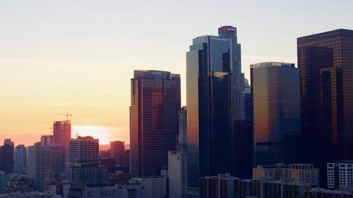 Modern buildings in city against sky during sunset