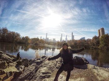 Portrait of woman standing at lakeshore against sky