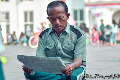 Mid adult man holding paper while standing on street