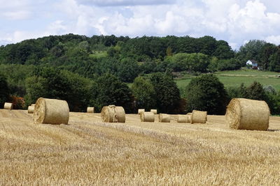 Hay bales on field against sky