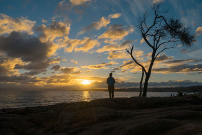 Silhouette woman on beach against sky during sunset