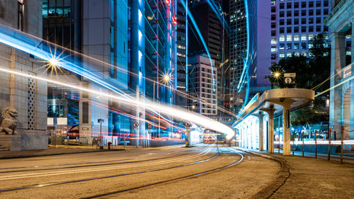 Light trails on street amidst buildings in city at night