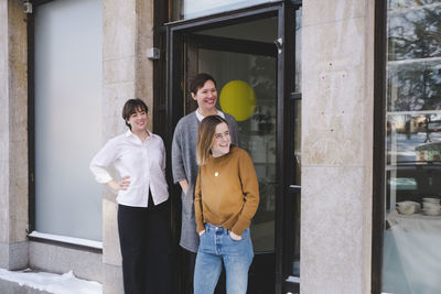 Smiling female design professionals standing at entrance of workshop