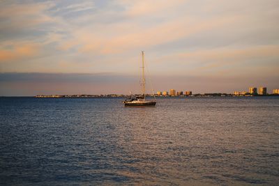 Sailboat sailing on sea against sky during sunset