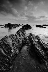 Scenic view of rocks on beach against sky