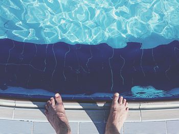 Low section of man by swimming pool on sunny day