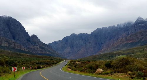 Road by mountains against sky