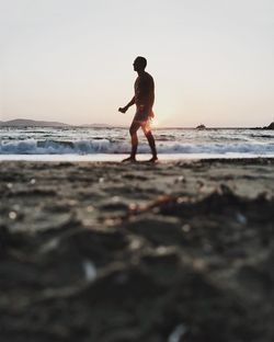 Full length of silhouette man standing on beach against clear sky