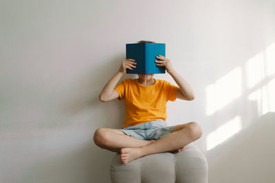 Rear view of woman with arms crossed against wall