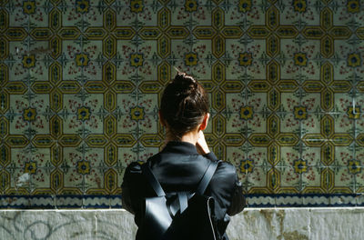 Rear view of woman standing against wall in building