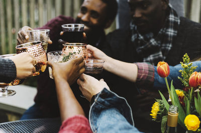 Happy friends toasting drinks while sitting in backyard