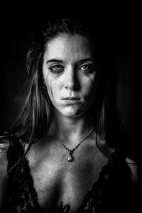 Portrait of sad young woman with smudged make-up against black background