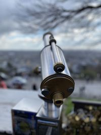 Close-up of coin-operated binoculars by hills against sky