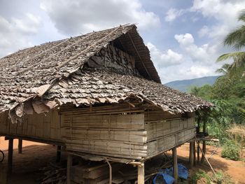 Built structure by trees and houses against sky