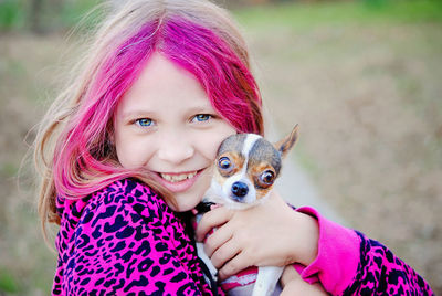 Portrait of a girl with pink hair holding puppy