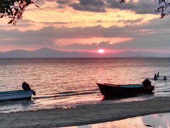 Boat moored on sea against sky during sunset