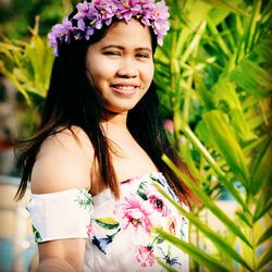 Portrait of a smiling young woman standing against plants