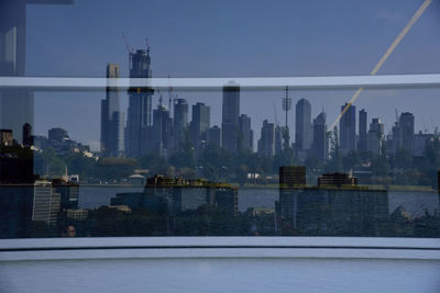 Modern buildings by river against sky in city