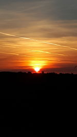 Scenic view of silhouette mountains against orange sky