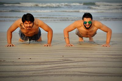 Young men doing push ups on beach