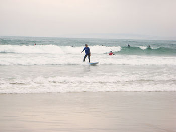 People at beach against sky