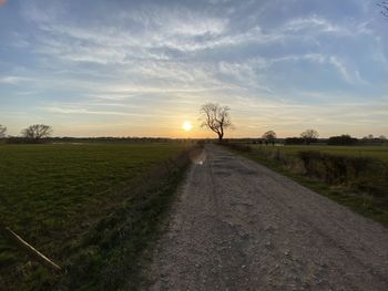 Road amidst field against sky