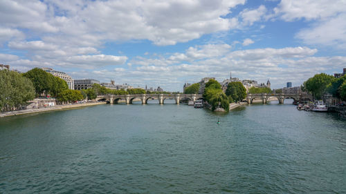 Arch bridge over river amidst buildings against sky