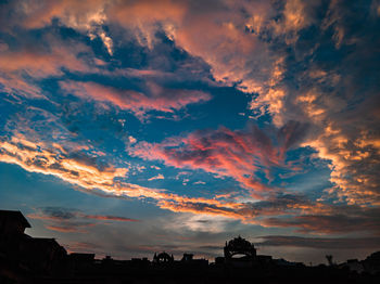 Silhouette buildings against dramatic sky during sunset
