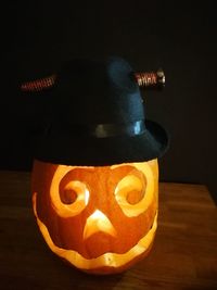 Close-up of illuminated lantern on table against black background