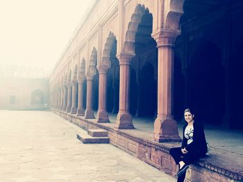 Portrait of woman sitting on seat at historic building