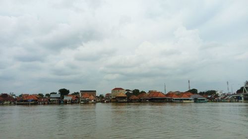 Buildings by river against sky in town