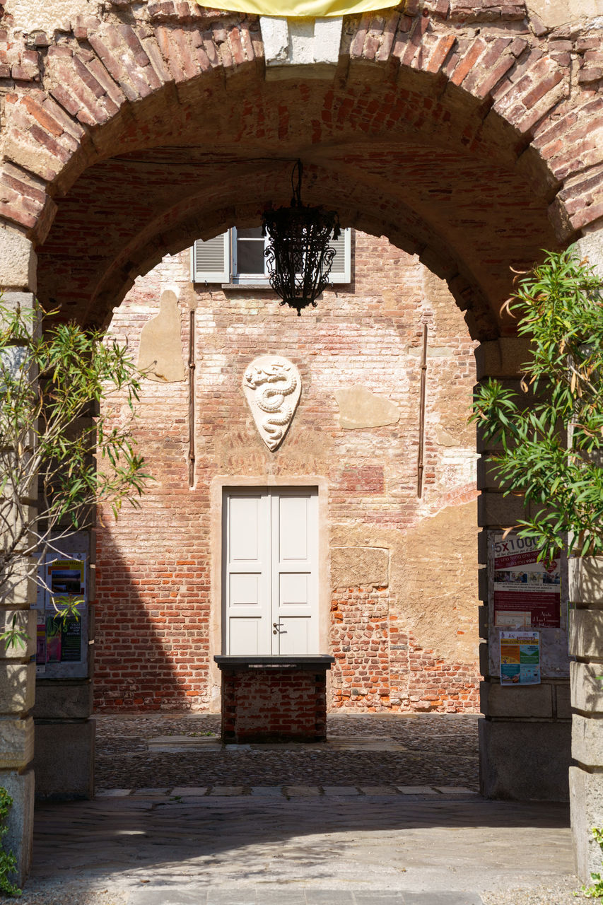 architecture, arch, built structure, entrance, door, building exterior, no people, building, day, gate, nature, history, sunlight, wall, the past, place of worship, plant, outdoors, brick, doorway, ancient history, wall - building feature, city, house, street, old, closed