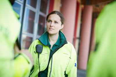 Female mid adult paramedic looking away while standing outside hospital