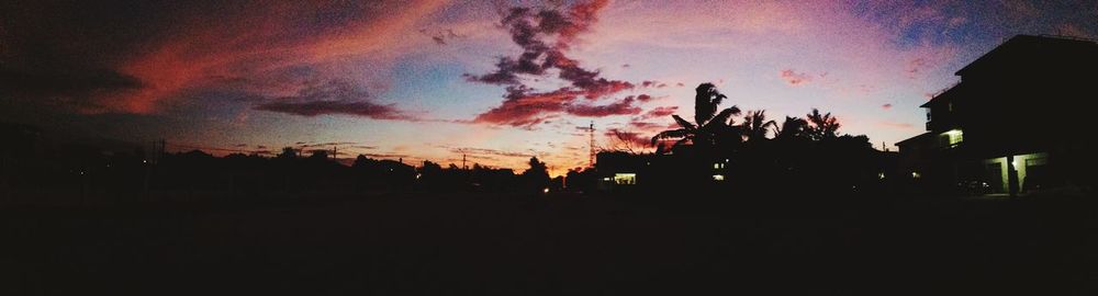 Low angle view of silhouette illuminated buildings against sky at sunset