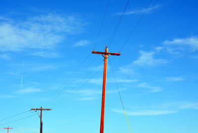 Low angle view of electricity pylon against blue sky