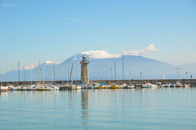 Sailboats moored at harbor against sky