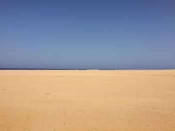 Scenic view of beach against clear blue sky