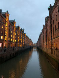 Canal amidst buildings in city against sky