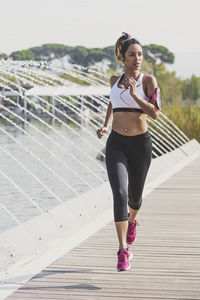 Full length portrait of young woman running by fountain