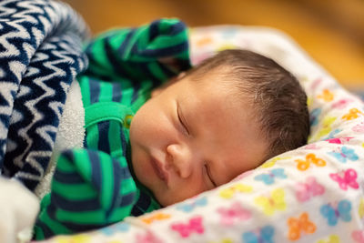 The infant baby sleeps in his bed, covered with a blanket