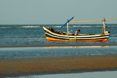 Boat moored on beach against clear sky