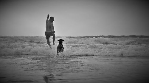 Man running with dog at beach