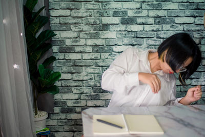 Rear view of woman sitting against wall