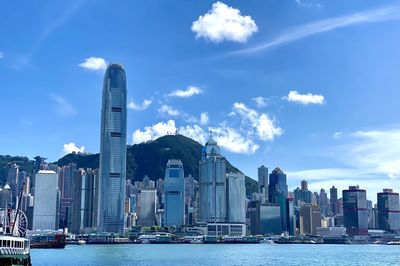 Sea by modern buildings against sky in city