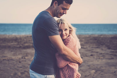 Couple kissing on beach against sky