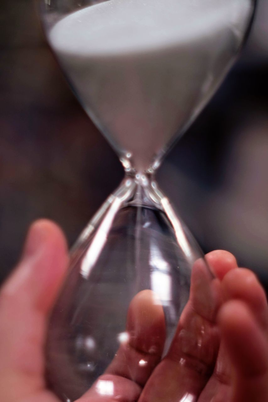 CLOSE-UP OF HUMAN HAND HOLDING GLASS IN SAND