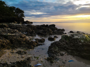 Rocks on beach against sky during sunset