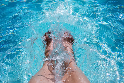 Low section of woman splashing water in swimming pool