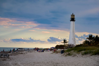 People on beach against cloudy sky